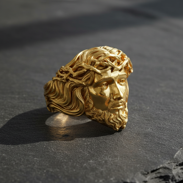 Gold-plated sterling silver Jesus ring displaying the lustrous finish on the sculptural portrait of Jesus, casting a shadow on a slate background.
