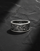 Front view of handcrafted silver baroque scroll ring featuring detailed acanthus leaf relief on black stone background