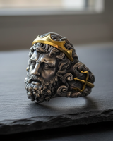 Front view of handcrafted silver Poseidon ring with gold crown accent and intense facial details on a dark stone background