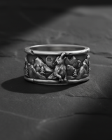 Side view of handcrafted silver wolf ring showing oxidized finish and pine tree relief details with rocky texture