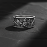 Side view of handcrafted silver wolf ring showing oxidized finish and pine tree relief details with rocky texture