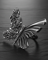 Close-up detail of silver butterfly ring highlighting the contrast between ribbed wing texture and flower motifs