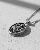 Angled view of silver Artemis necklace showing floral border details and oxidized finish on goddess figure
