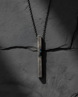Handcrafted oxidized silver pendant with industrial design and geometric shape on grey surface