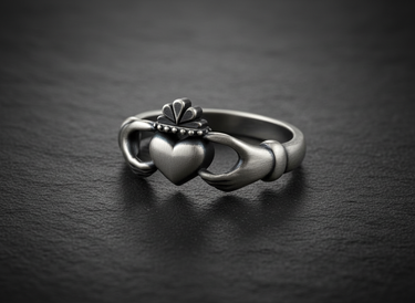 Front view of antique style 925 sterling silver Claddagh ring with crowned heart displayed on black stone background