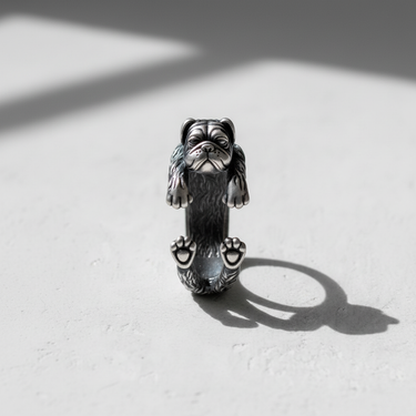 Front view of detailed silver dog ring featuring realistic pug face and paws resting on surface with shadow