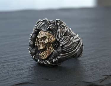 Close up of two tone skull ring with brass skull center and silver raven perched on top for gothic style fashion
