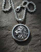 Full view of handcrafted silver lion necklace with chain displayed on a natural slate surface with clasp visible