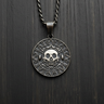 Oxidized 925 sterling silver Aztec skull coin pendant centered on dark wood background