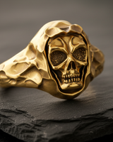 Side angle view of gold hooded skull ring showing hammered metal texture and grim reaper design on dark background