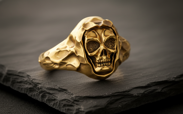 Side angle view of gold hooded skull ring showing hammered metal texture and grim reaper design on dark background