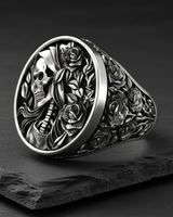 Angled shot of silver reaper rose ring showing deep relief carving of the skull profile and floral vines on the band