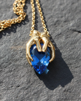 Detailed side profile of sterling silver hands setting holding a large teardrop gemstone for necklace