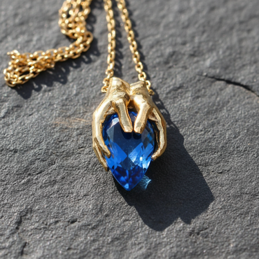 Detailed side profile of sterling silver hands setting holding a large teardrop gemstone for necklace