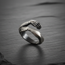 925 sterling silver hug ring featuring two hands wrapping around finger on dark stone background