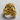 Rose gold Zeus ring from a side profile, displaying the flowing hair and band design against a light gray textured background.