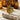 Lifestyle shot of gold vermeil sun pendant variant displayed on textured stone with amber bottles
