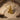 Golden variant of dreaming cherub pendant displayed on textured sand background with driftwood accents