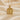 Gold vermeil version of Vitruvian Man pendant necklace displayed on beige silk fabric