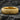 Gold tone snake skin ring displaying intricate serpent scale pattern resting on a dark textured stone