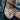 Close-up of rustic silver triangle necklace featuring black gemstones and deep cracked earth texture