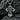 Close-up of the Jesus cross pendant resting on dark rocks highlighting the crown of thorns and oxidized finish