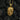 Close-up of the 14K gold vermeil octopus skull pendant resting on dark charcoal pieces highlighting its texture