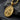 Close-up of gold Sacred Heart medallion resting on a textured dark stone surface with matching chain