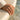 Elegant vintage scrollwork ring worn on a woman's hand resting gracefully against a textured stone surface near water