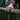 Lifestyle shot of the oxidized silver pharaoh skull ring worn on a man's hand holding a wooden axe handle in the forest