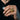 Lifestyle shot of man wearing heavy sterling silver blacksmith signet ring holding dark sunglasses against black shirt