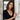 Young woman wearing an oxidized silver turtle pendant on a thin chain standing by a rustic wooden door frame