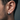 Close-up of minimalist industrial hoop earring in oxidized silver worn on a man's ear showing the sleek brutalist design