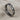 Close-up view of handcrafted eternity heart ring resting on textured fabric showing oxidized silver finish