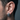 Close-up of man wearing oxidized silver skull hoop earring showcasing huggie style fit and deep oxidized eye sockets.