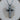 Close-up of handcrafted rustic cross pendant showcasing antique nail details and oxidized silver finish resting on a log
