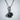 Rose Thorn Pendant, black rhodium, front view against wall
