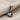 Handcrafted tobacco pipe pendant in oxidized silver hanging from a chain, resting elegantly on textured beige fabric