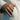 Lifestyle view of handcrafted eagle ring worn on a man's finger resting near a light textured fabric garment.