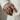 Detailed view of oxidized silver speaker ring worn on a man's finger with beige suit for style context