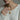 Model wearing delicate violet flower pendant necklace on gold chain over white knitted sweater background