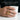 Close up of handcrafted Masonic carnelian shield thumb ring worn on hand holding a white ceramic cup