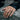 Close-up view of a hand wearing a solid sterling silver ram ring on a rustic natural stone background