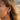 Model wearing the Garnet Brutalist Earring showing the rugged single huggie hoop fit on earlobe.