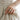 Person wearing oxidized silver hugging hands ring on index finger holding linen dress in close-up view