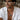 Male model wearing oxidized silver aviator wings pendant necklace on chain paired with open white linen shirt