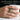 Baroque Cross Ring, oxidized silver, worn on model hand holding a cup
