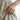 Minimalist open rope ring gold ends in sterling silver worn on woman hand against natural linen fabric background