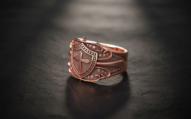 Rose gold vermeil cross ring with detailed beaded borders on dark stone background