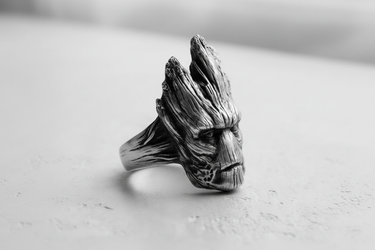 Side profile of silver Groot ring showing intricate wood grain carving and rugged design on grey background